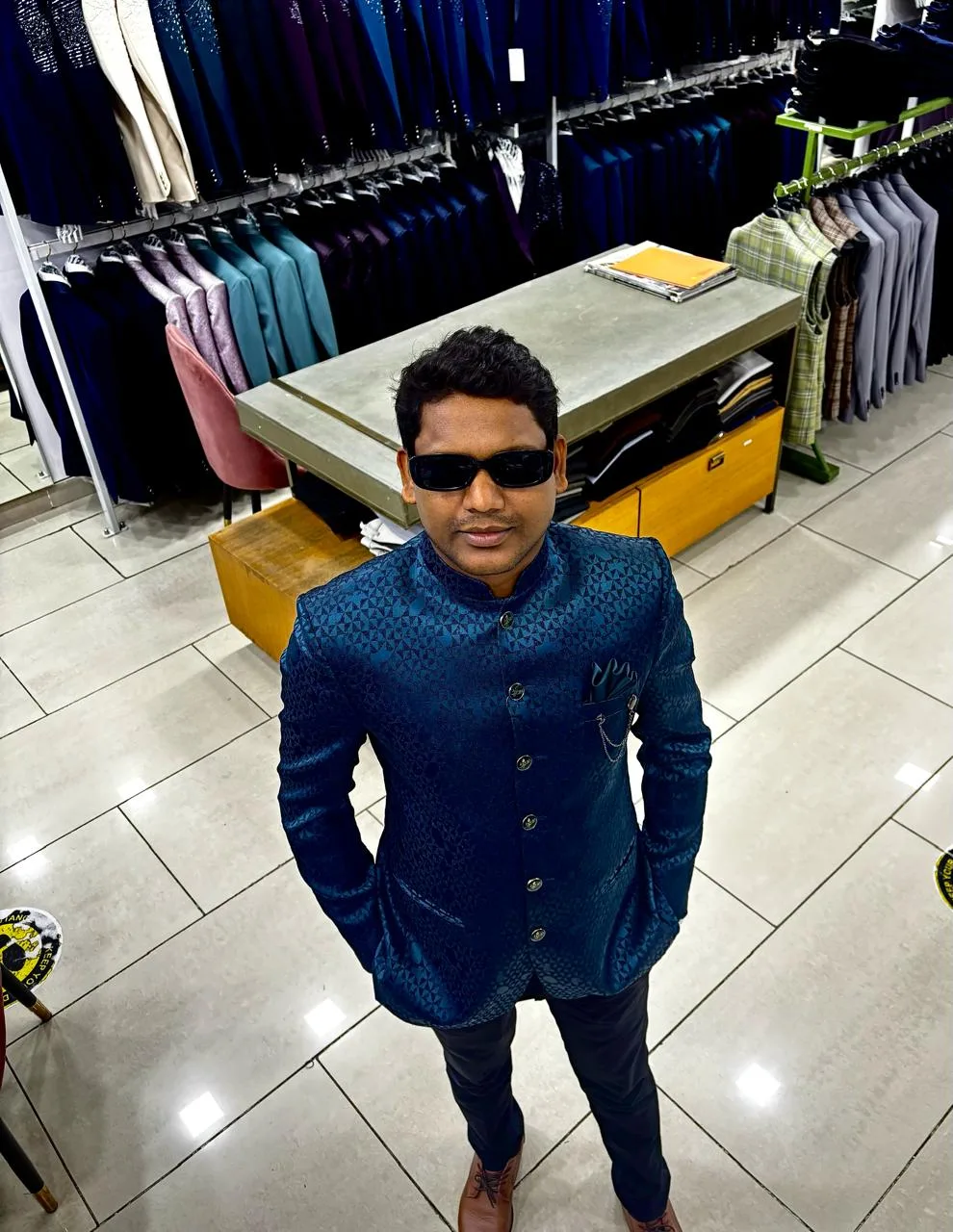 Customer in a teal self-textured bandhgala jacket with a pocket square on the Bespoke Studio retail floor