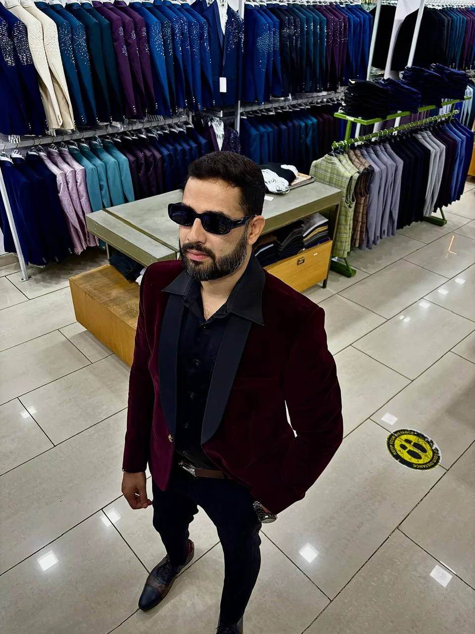 Customer in a maroon velvet tuxedo blazer with a satin shawl lapel on the Bespoke Studio retail floor